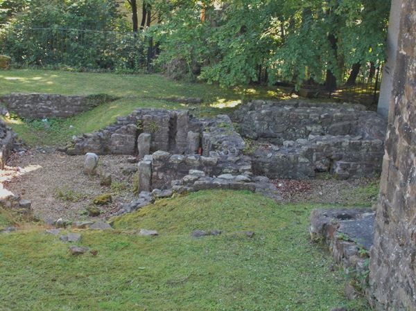 Photo of the remains of the Roman Bath House: low sections of stone walls and brick stacks that once supported the floor above the hypocaust system.